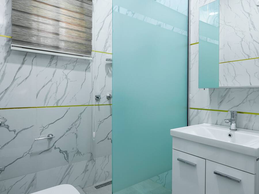 Un baño moderno con cabina de ducha de vidrio, inodoro, lavabo y espejo.