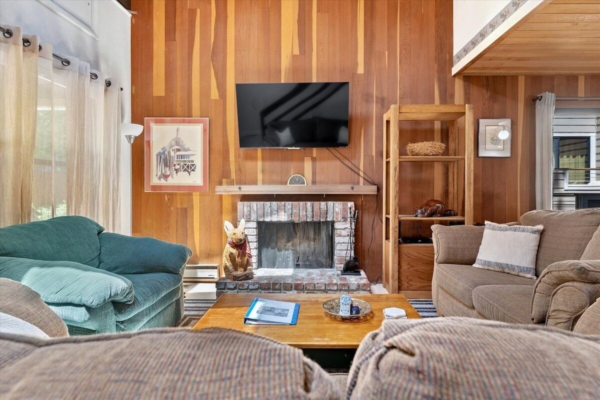 Ein gemütliches Wohnzimmer mit Kamin, Wandfernseher und Bücherregal.