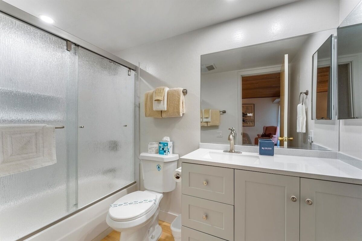 Une salle de bain avec une douche à parois de verre, des toilettes, un lavabo avec un miroir et une serviette accrochée au mur.