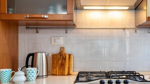 A kitchen with a built-in gas stove, wooden cabinets, and a tiled backsplash. - Casa Grace in Alghero (Alghero)