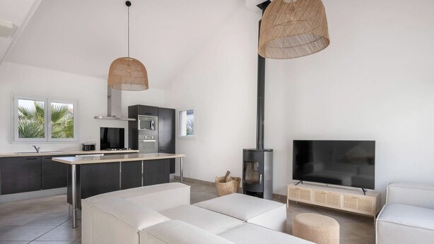 Una sala moderna con un sofá, un televisor y una zona de cocina con estufa.