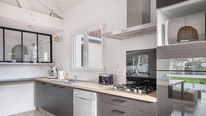Una cocina moderna con lavavajillas integrado, estufa y un amplio ventanal que proporciona luz natural.