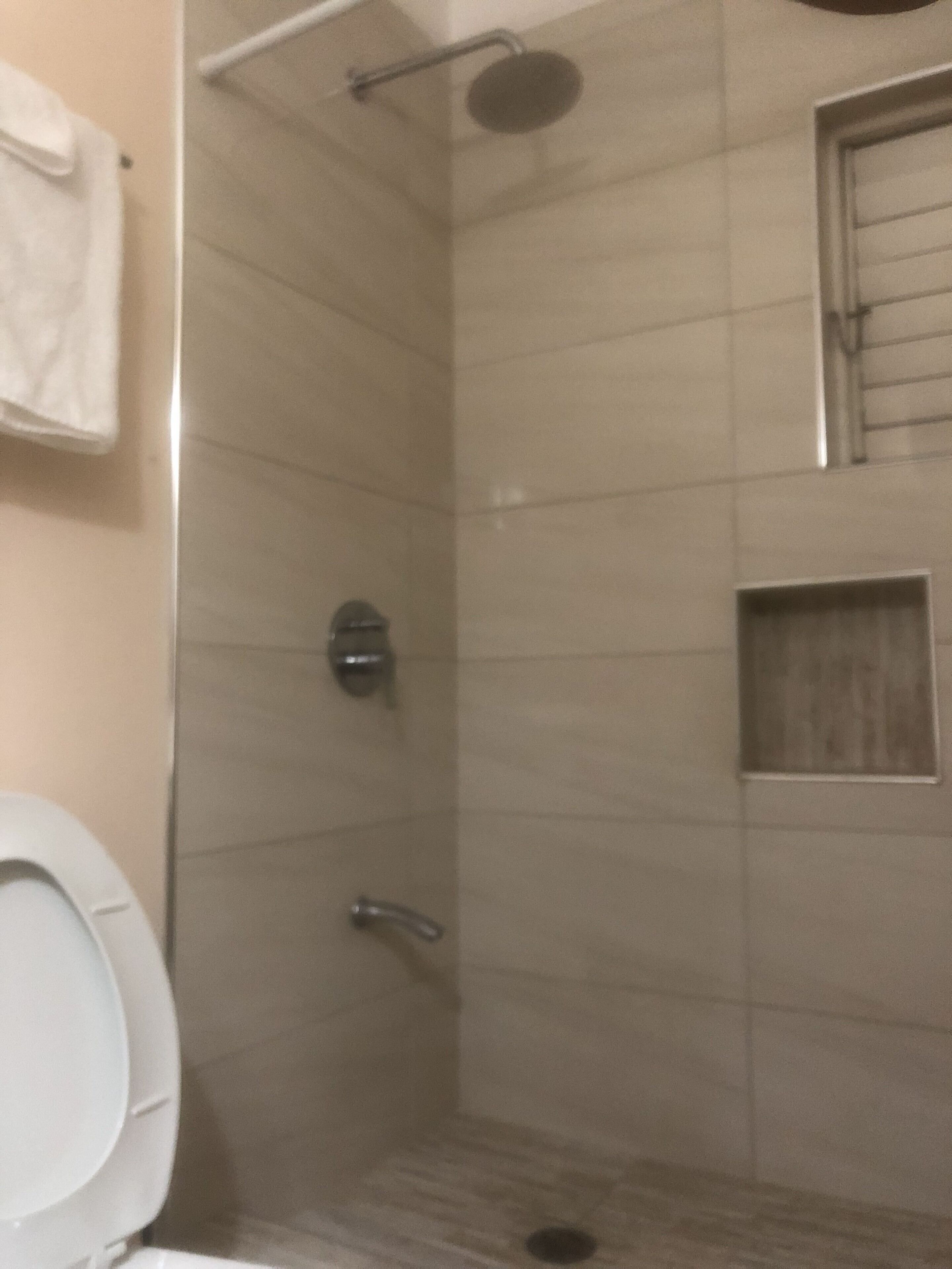 Une salle de bain avec une douche, des toilettes et un porte-serviettes.