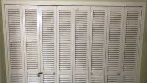Quarto com guarda-roupa espaçoso, soalho em azulejo e colcha estampada.