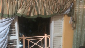 Sala de estar com sofá, varanda com guarda-corpo e porta para o exterior.