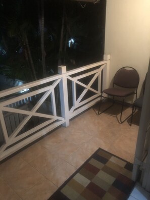 A balcony with a white railing, a chair, and a patterned rug. - Finest Accommodation Renfrew Place  (Kingston)