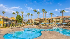 Un resort con una amplia piscina, palmeras y varias zonas de descanso.
