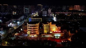 Un hotel de varios pisos con un atrio central, rodeado de estacionamiento y otros edificios.