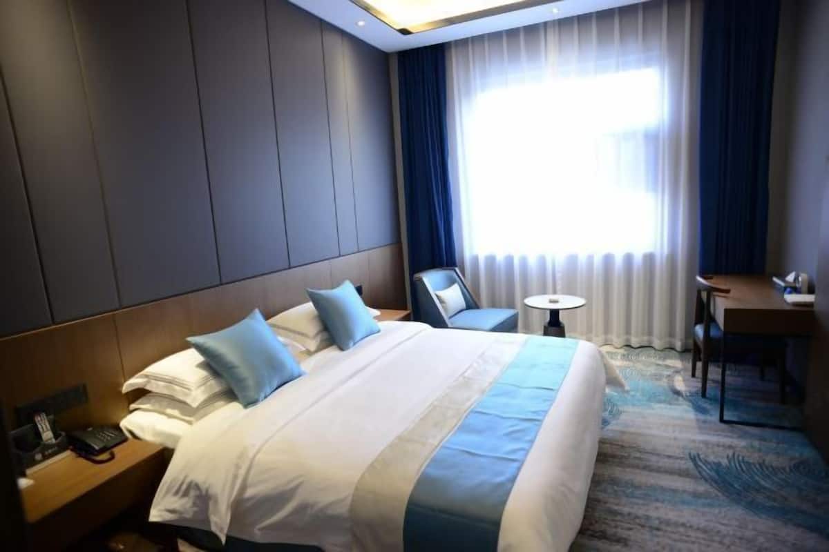 Una habitación de hotel con una cama grande, un escritorio y una silla.