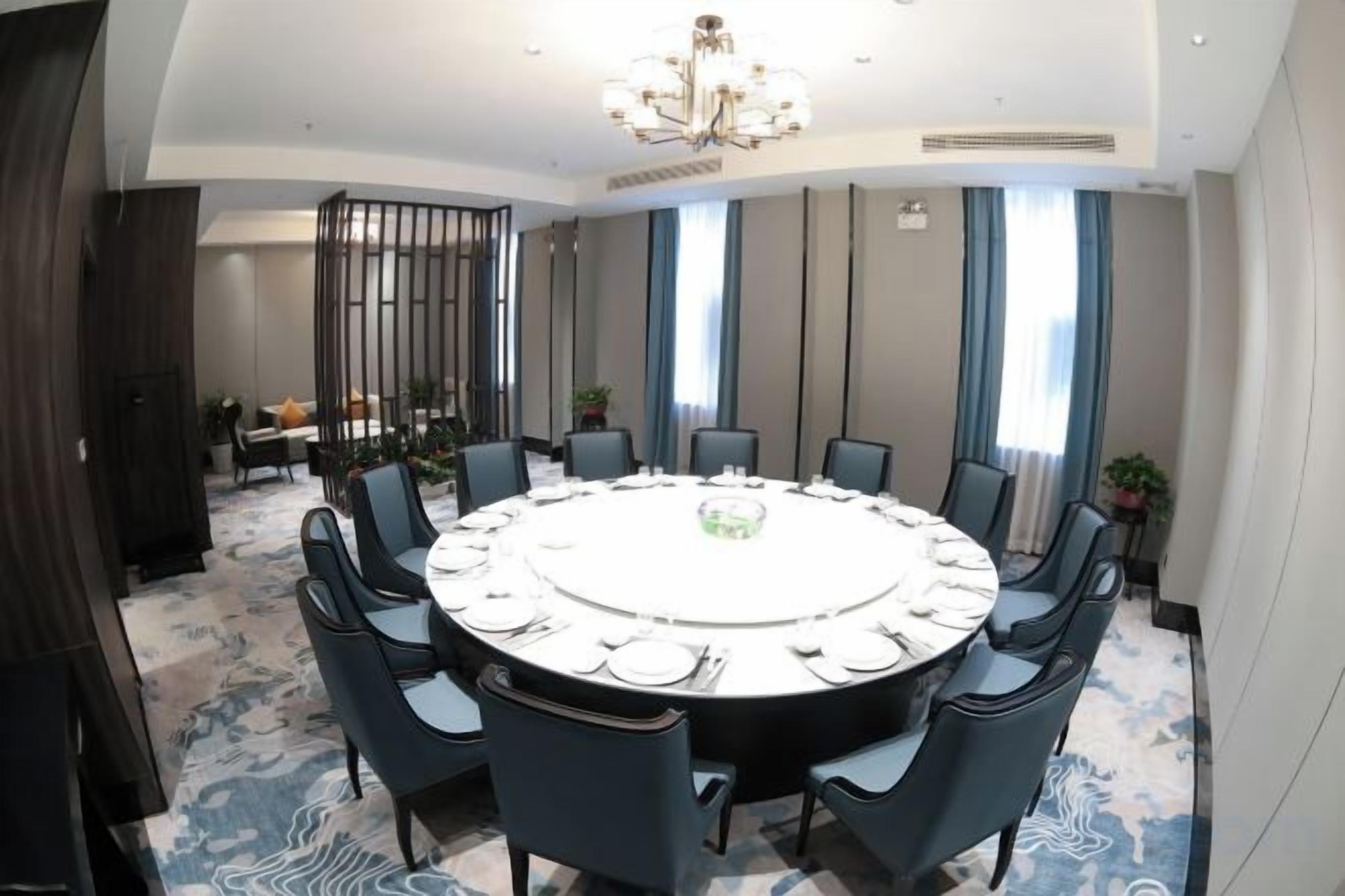 A conference room with a round table, chairs, and a chandelier.