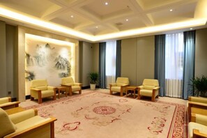 A conference room with a large carpet, several chairs, a wall with artwork, and a window with curtains. - Yanshi Hotel (Luoyang)