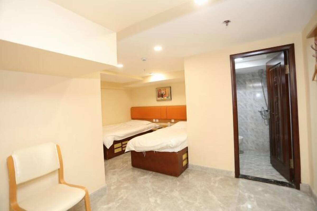 A room with two beds, a chair, and a door leading to a bathroom.