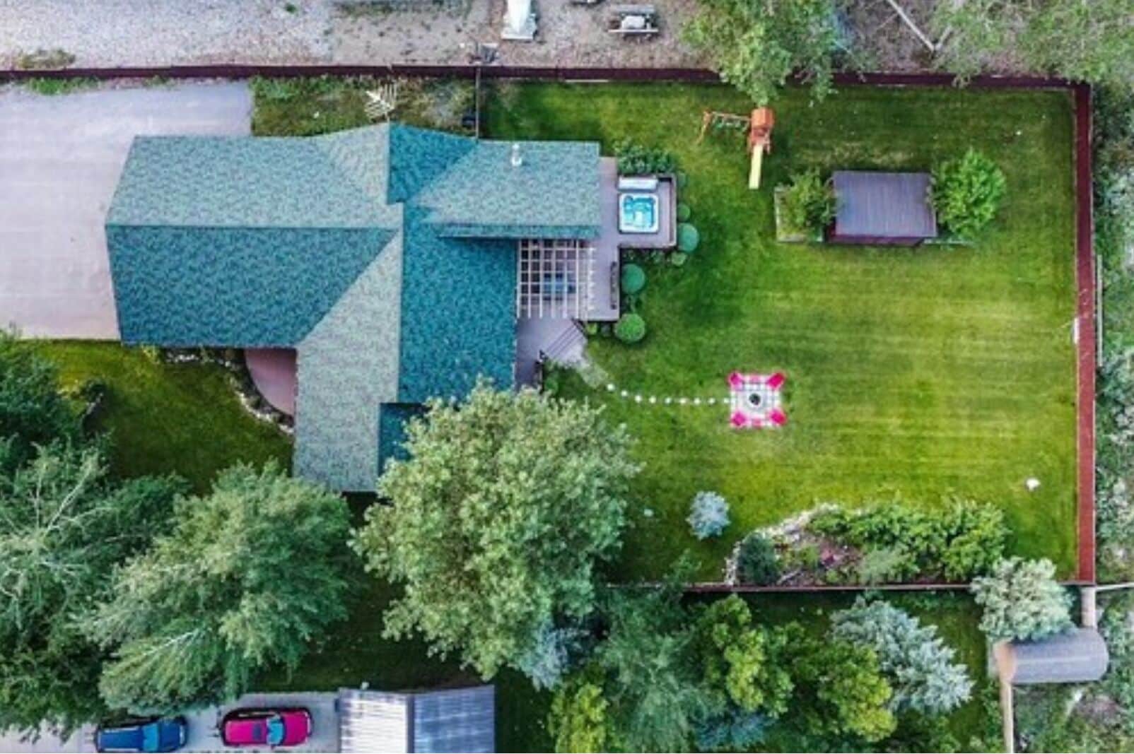 Una casa con un ampio giardino, una piscina e un'area giochi recintata.