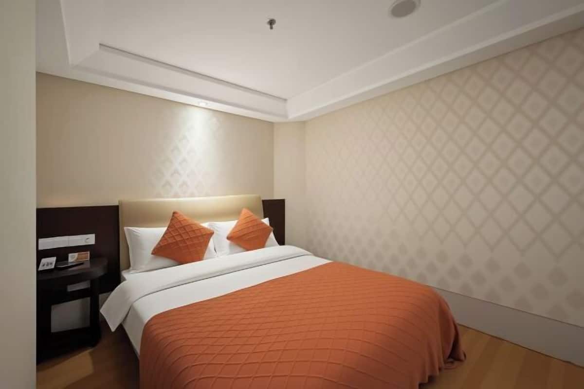 A hotel room with a bed, nightstand, and a patterned wall.