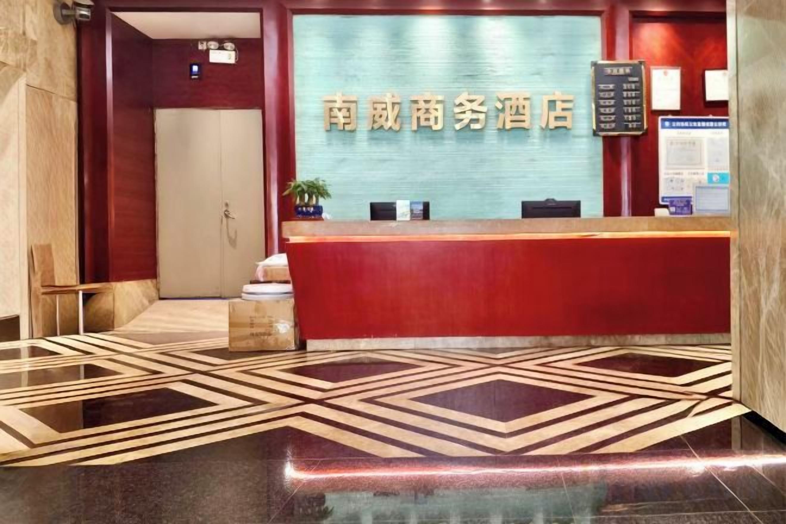 A hotel reception area with a red reception desk, a glass partition, and a patterned floor.