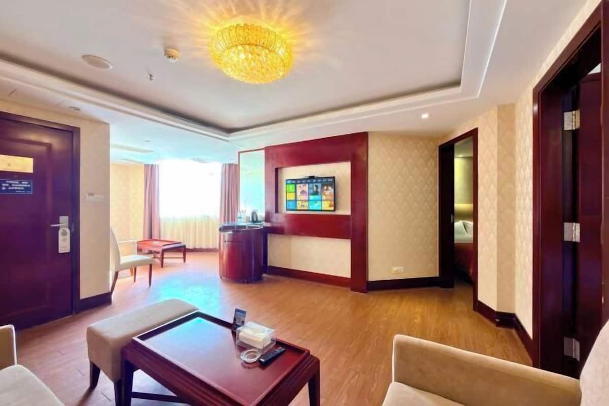 A hotel lobby with a reception desk, seating area, and a chandelier.