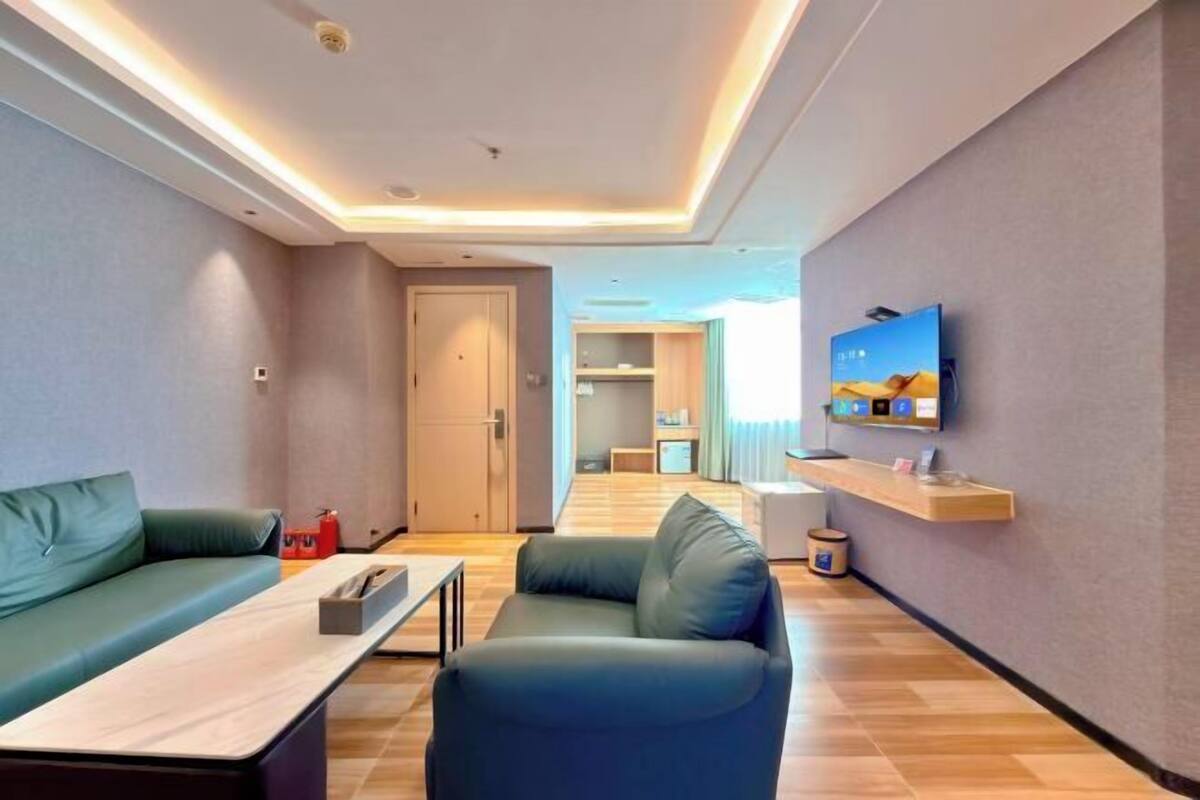 A modern living room with a sofa, a coffee table, a TV mounted on the wall, and a wooden floor.