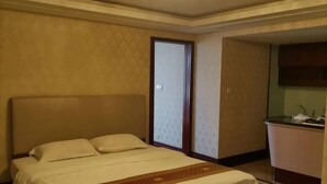 Una habitación de hotel con una cama, un pequeño kitchenette y una puerta que da a otra habitación.