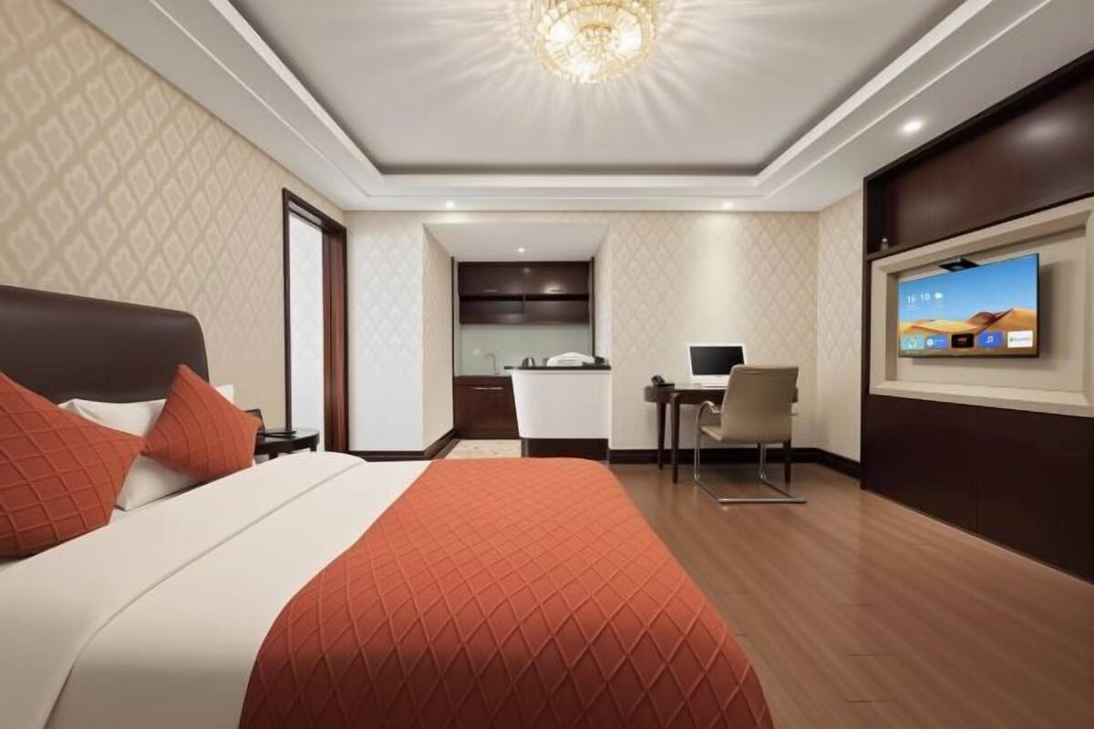 A hotel room with a bed, a desk, a TV, and a bathroom.