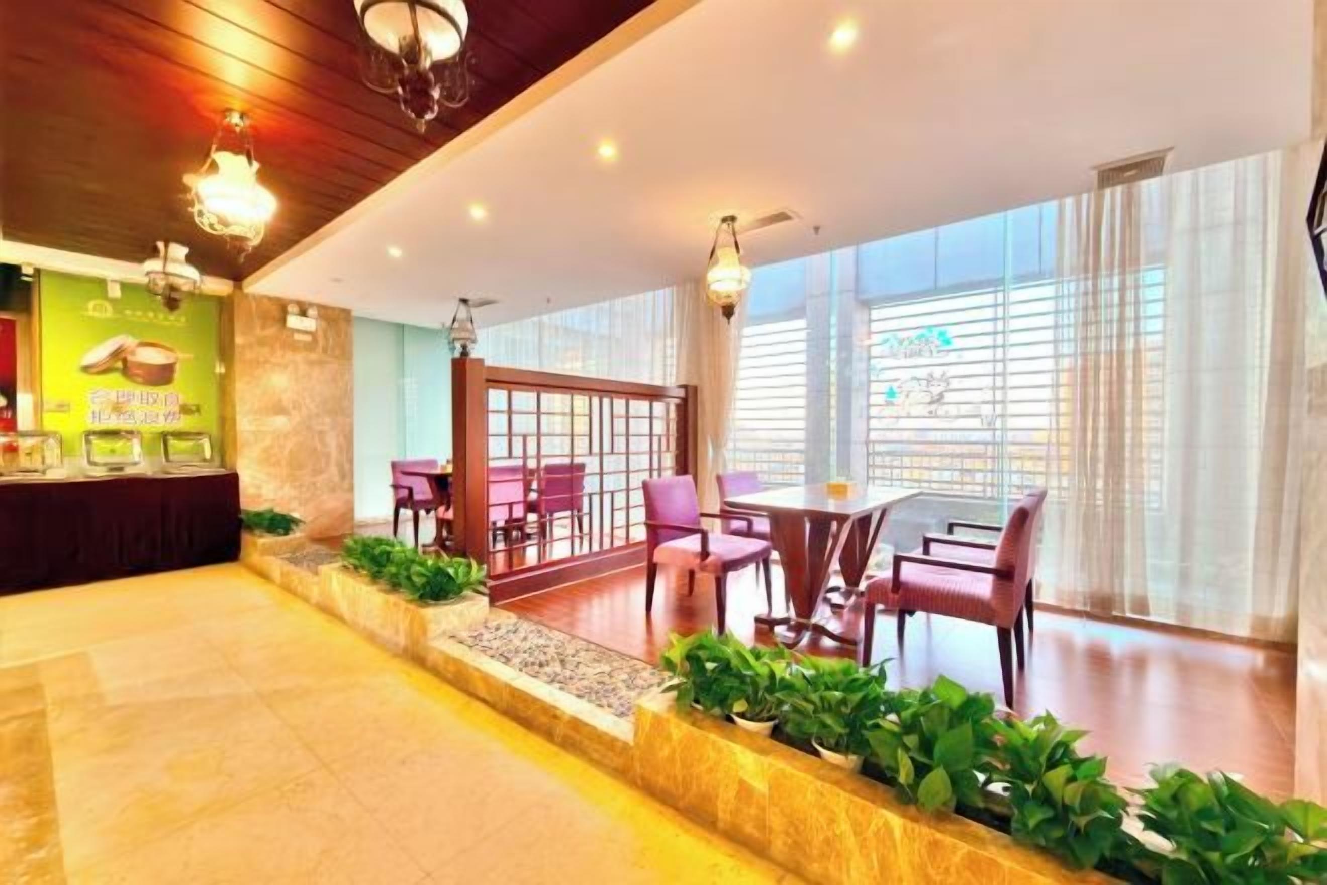 A hotel lobby with a reception desk, seating area, and large windows.
