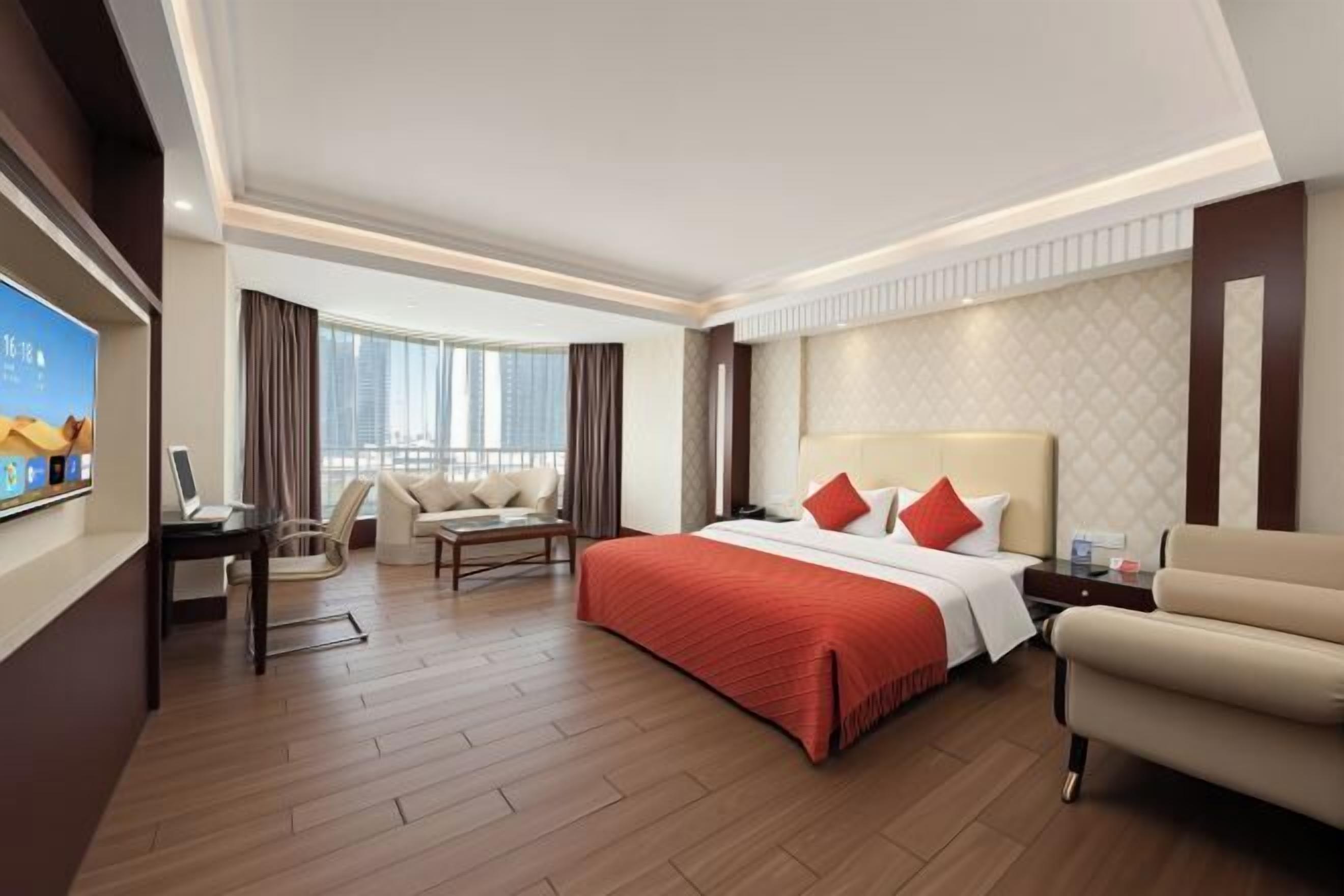 Une chambre d’hôtel avec un grand lit, un bureau, une chaise, un canapé et une télévision.