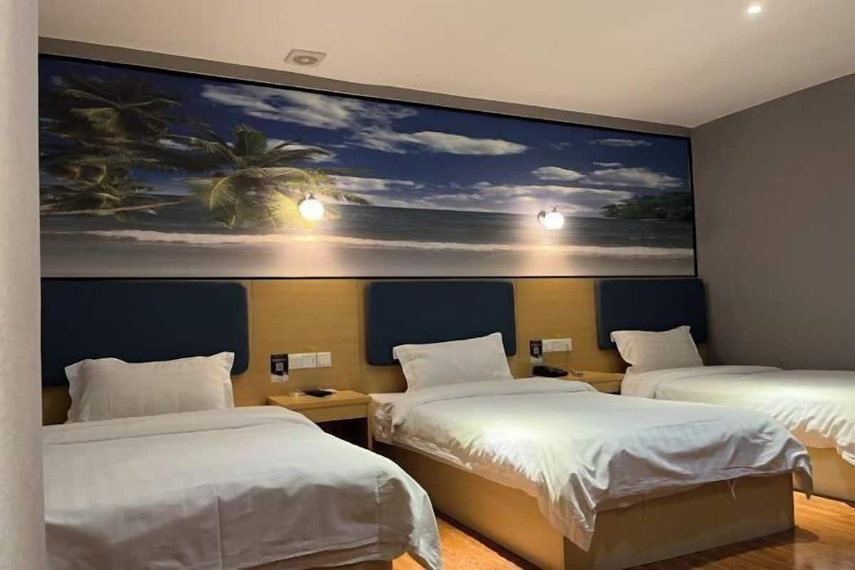 A hotel room with three beds, a large tropical mural on the wall, and a wooden headboard.