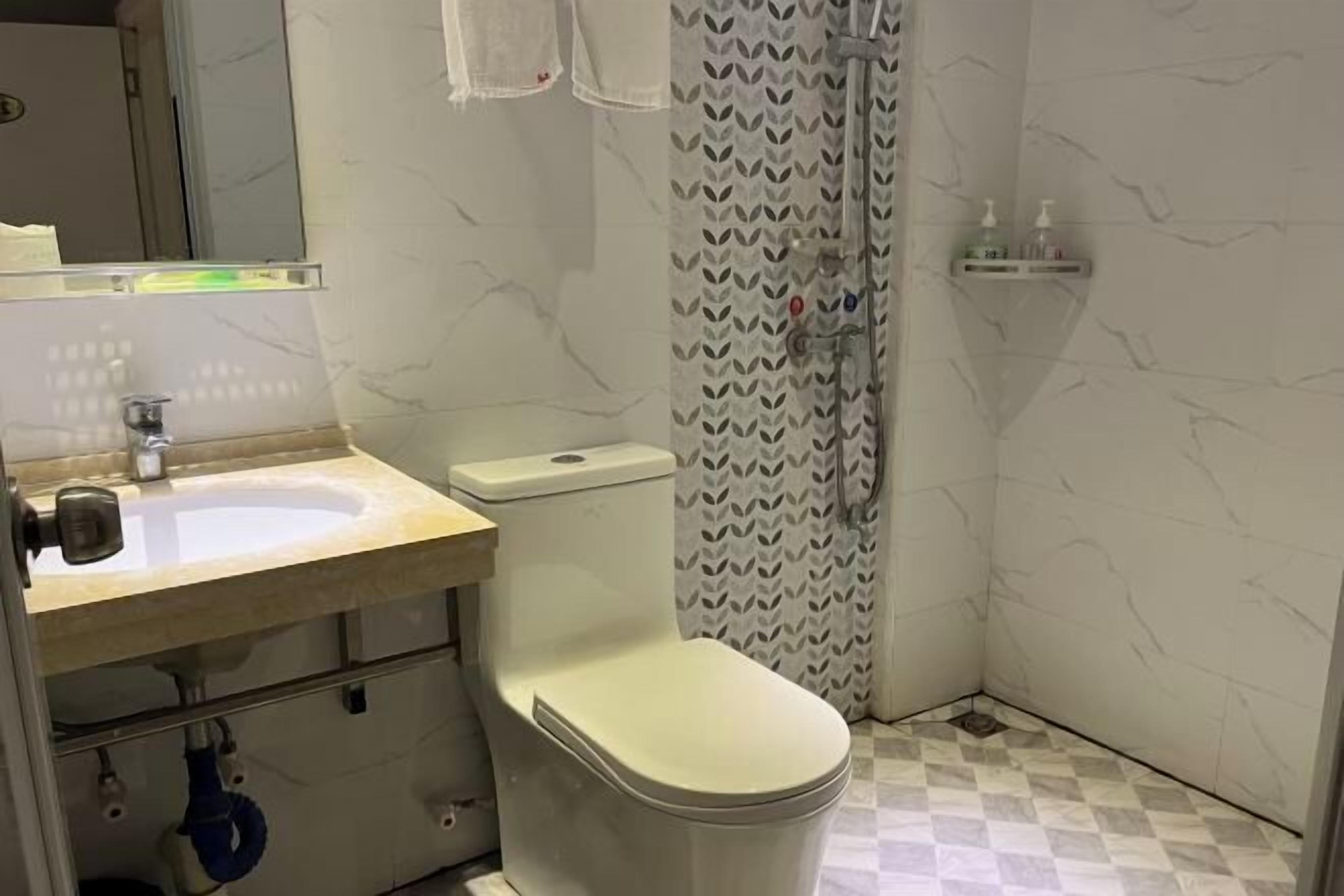 A bathroom with a toilet, sink, and shower.