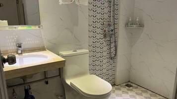A bathroom with a toilet, sink, and shower.
