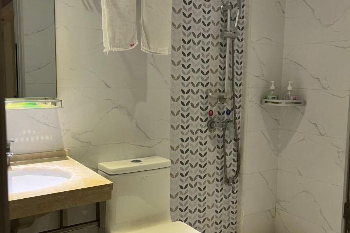 A bathroom with a marble sink, a toilet, and a shower with a patterned curtain.