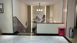 A hotel lobby with a reception desk, a staircase, and a mural of mountains. - Zhicheng Youpin Hotel (Yingbin Avenue) (Jiangmen)