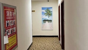 A hallway with a patterned floor, a poster with safety instructions, and a large painting of a beach scene. - Zhicheng Youpin Hotel (Yingbin Avenue) (Jiangmen)