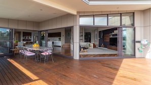 A modern house with a spacious deck, large windows, and a kitchen area.