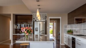 A modern kitchen with a central island, stainless steel appliances, and a pendant light.