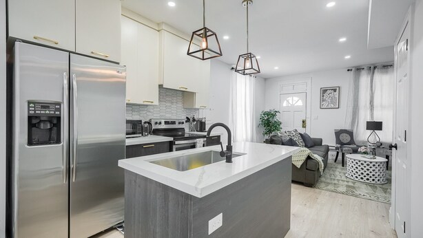 A modern kitchen with a central island, stainless steel appliances, and pendant lighting. - Modern Niagara-area Spa-like Home (St. Catharines)