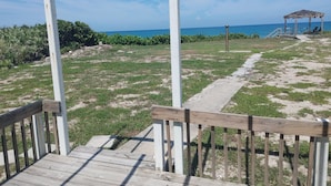 A wooden deck leading to a beach area with a gazebo and a pathway. - Melbourne Beach House and Basement Apt on 1.2 acres ocean front (Melbourne Beach)