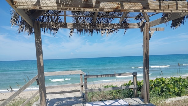A wooden deck leading to a beach with a wooden pergola overhead. - Melbourne Beach House and Basement Apt on 1.2 acres ocean front (Melbourne Beach)
