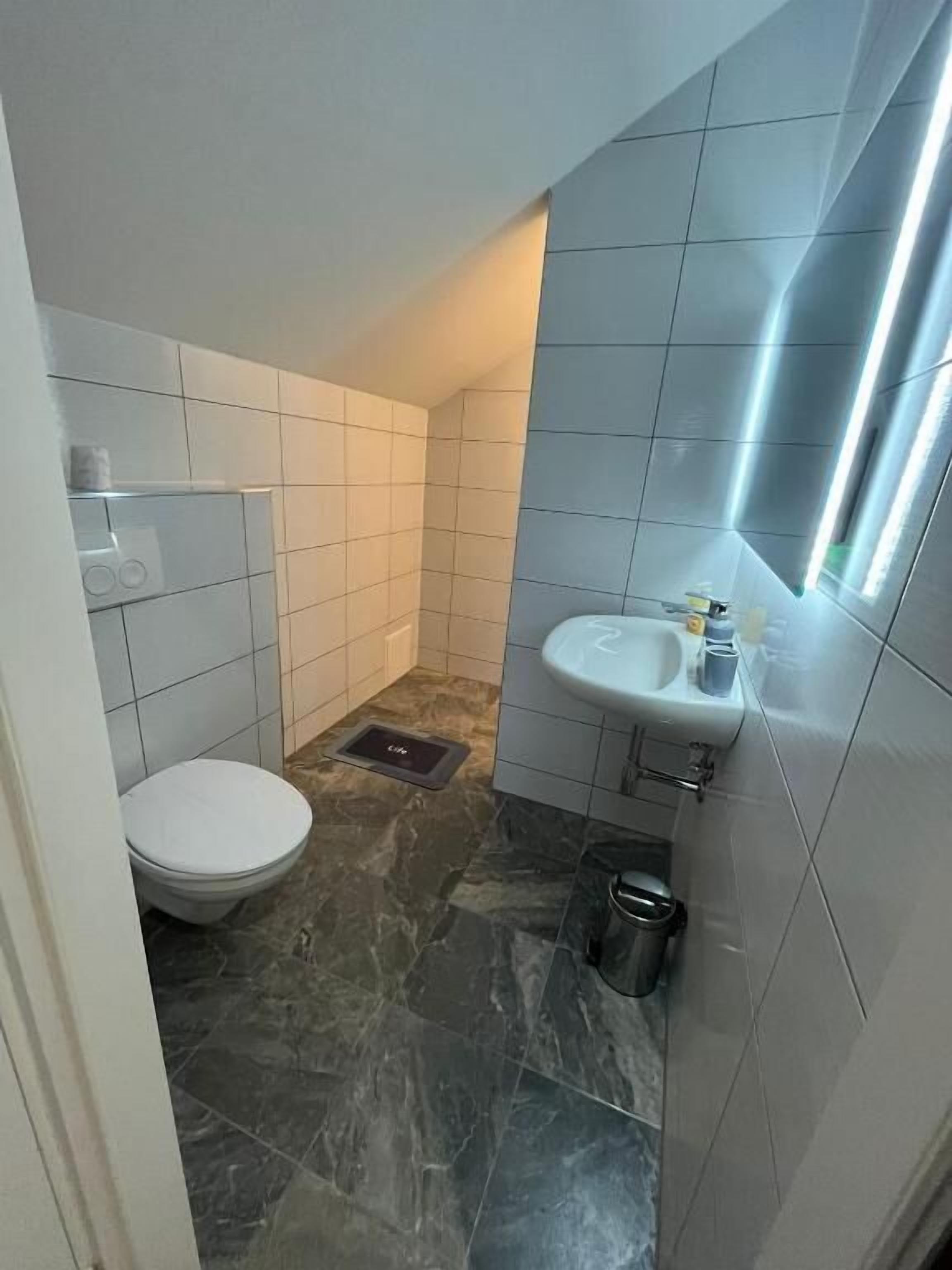 Un baño pequeño con inodoro, lavamanos y espejo.