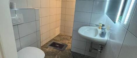 Un baño pequeño con inodoro, lavamanos y espejo.