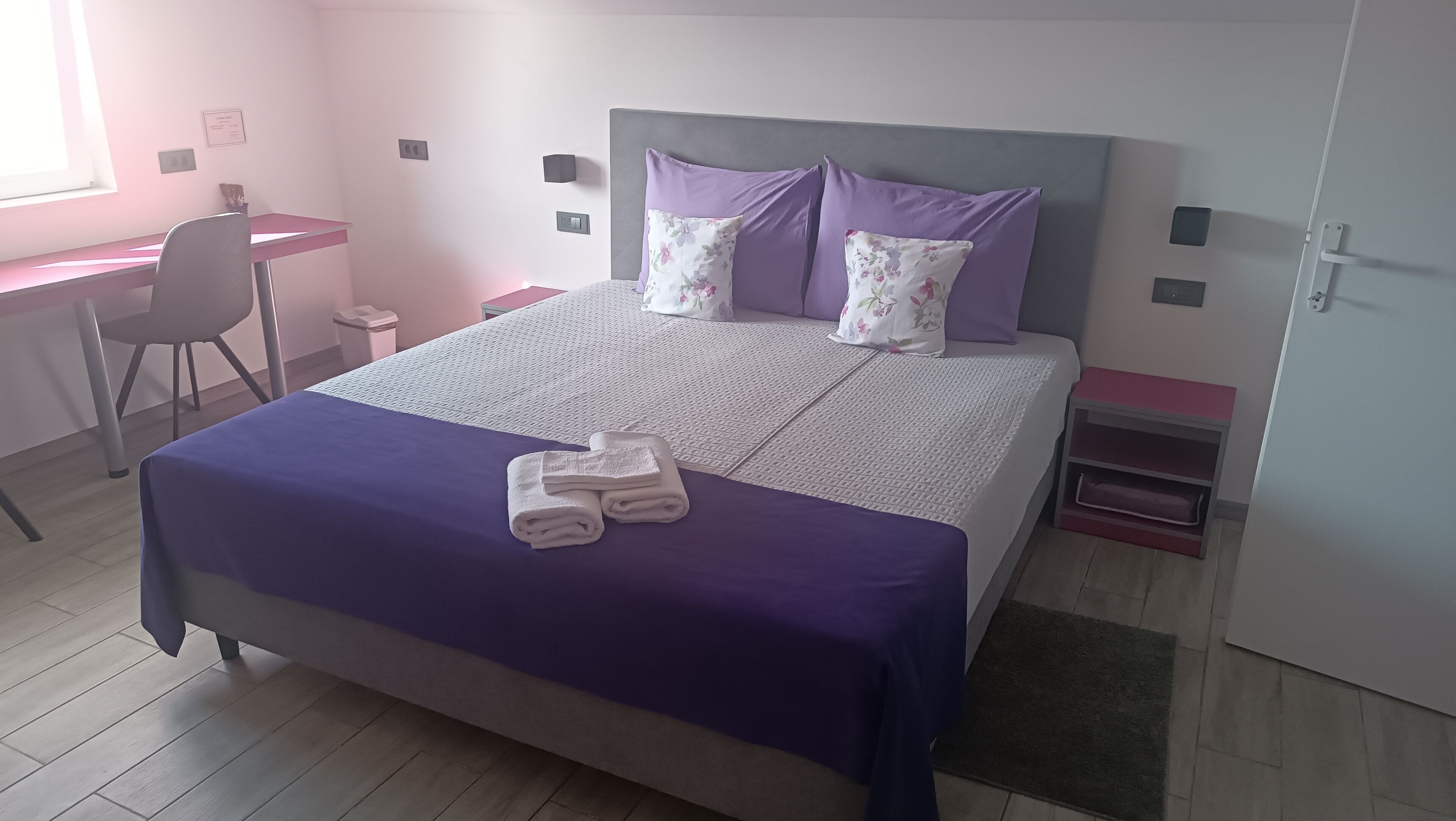 Un dormitorio ordenado con cama, escritorio y silla.