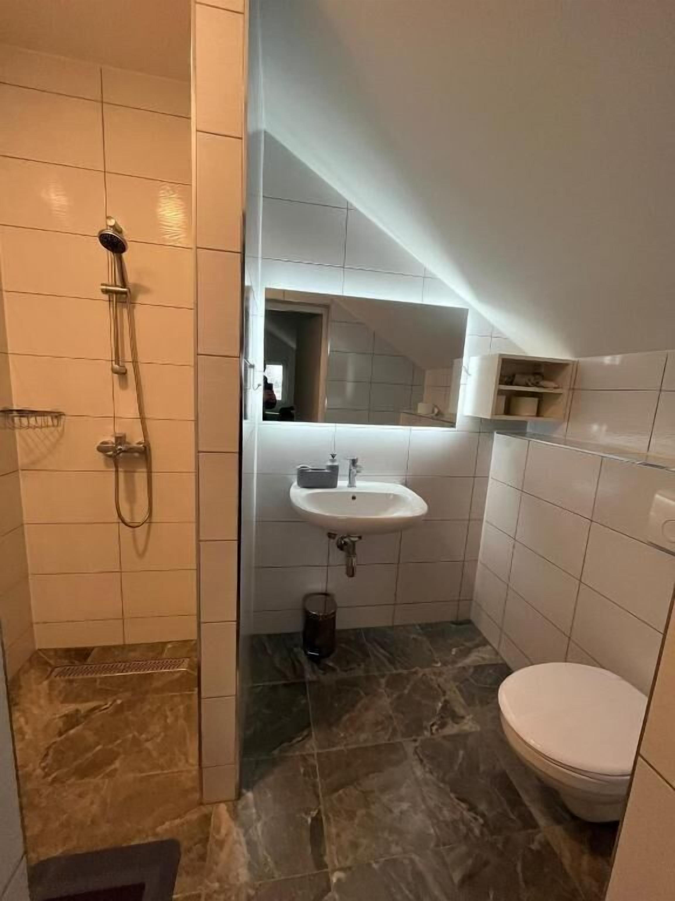 A small bathroom with a shower, a sink, and a toilet.