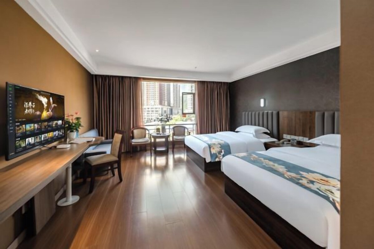 A hotel room with a bed, desk, chair, and a television.