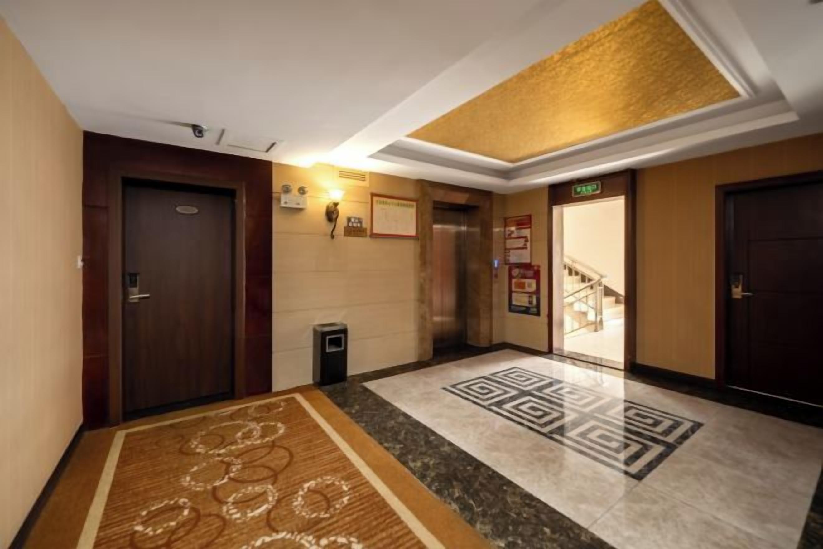 Um hall de hotel com piso coberto por carpete, um balcão de recepção e uma escadaria para um andar superior.