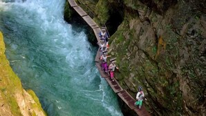 A wooden walkway along a river with people walking. - Hengda Hotel (High-speed Railway Station Branch) (Tongren)