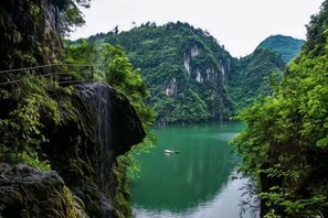 Un étroit canal bordé de falaises abruptes et couvertes de forêts, avec un petit bateau au centre.