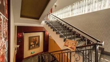 A staircase with a handrail, a door with a framed picture, and a wall with patterned wallpaper.