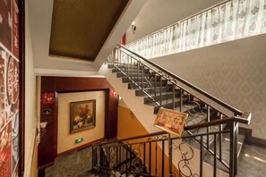 A staircase with a handrail, a door with a framed picture, and a wall with patterned wallpaper. - Hengda Hotel (High-speed Railway Station Branch) (Tongren)
