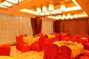 A banquet hall with round tables, red chairs, and a patterned wall. - Hengda Hotel (High-speed Railway Station Branch) (Tongren)