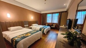 Habitación de hotel con dos camas, televisión, escritorio y espejo.
