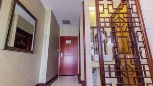 Un pasillo con un espejo, una puerta y un biombo de madera decorativo.