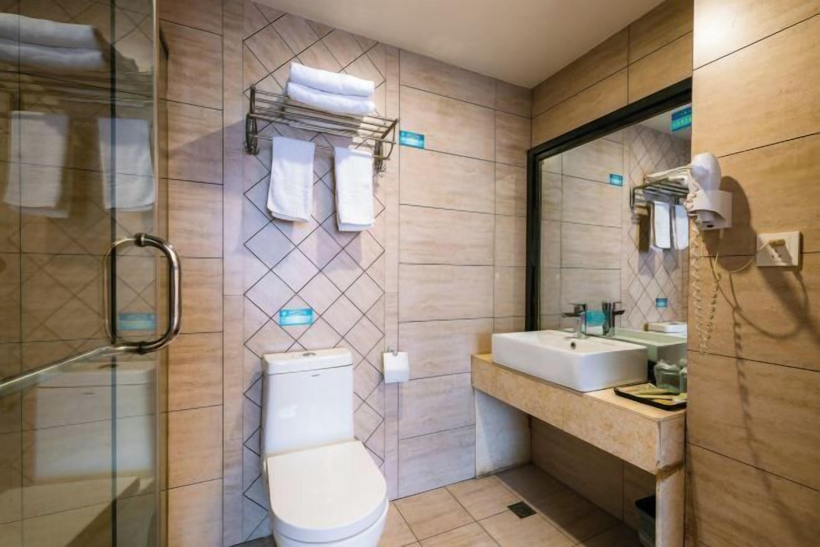 A modern bathroom with a glass shower enclosure, a toilet, a sink with a mirror, and a towel rack.